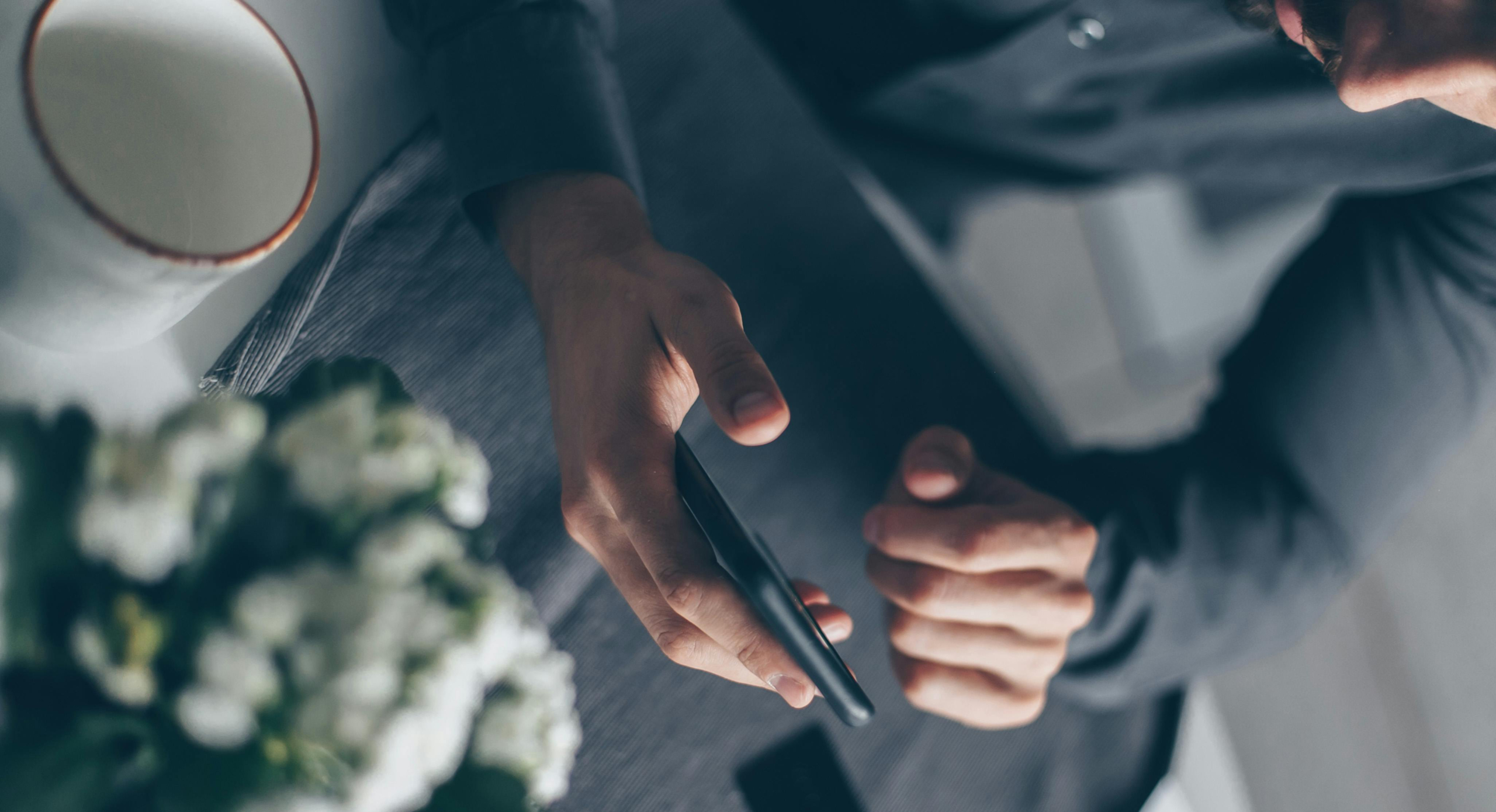 Een anonieme man gebruikt geheimzinnig zijn telefoon om een andere persoon dan zijn partner te contacteren. Enkel zijn handen en de telefoon zijn zichtbaar.
