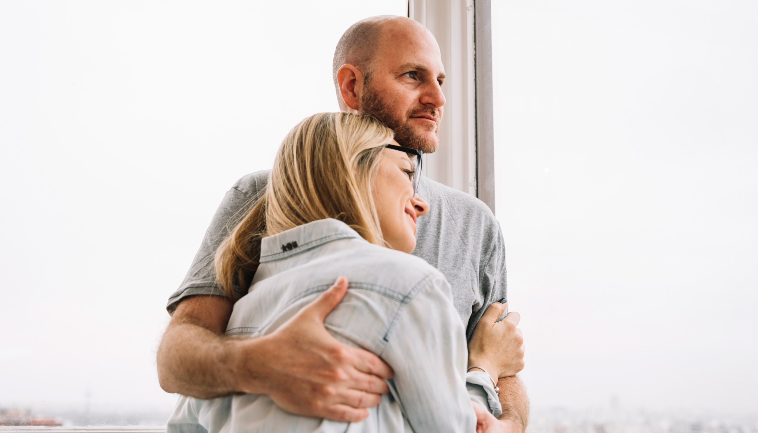 Een stel kijkt liefdevol uit het raam terwijl ze elkaar omhelzen