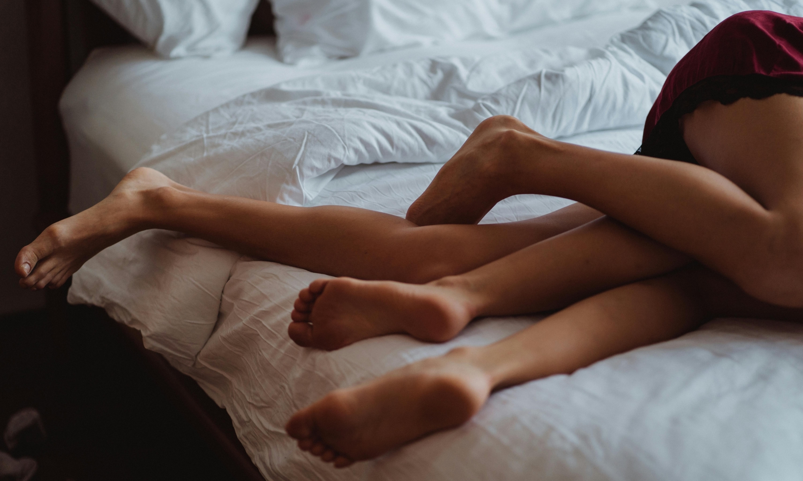 Een intiem moment tussen twee geliefden. We zien twee paar benen met elkaar verstrengeld op bed.