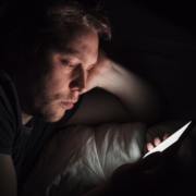 Man is gefixeerd op zijn telefoonscherm in het donker.